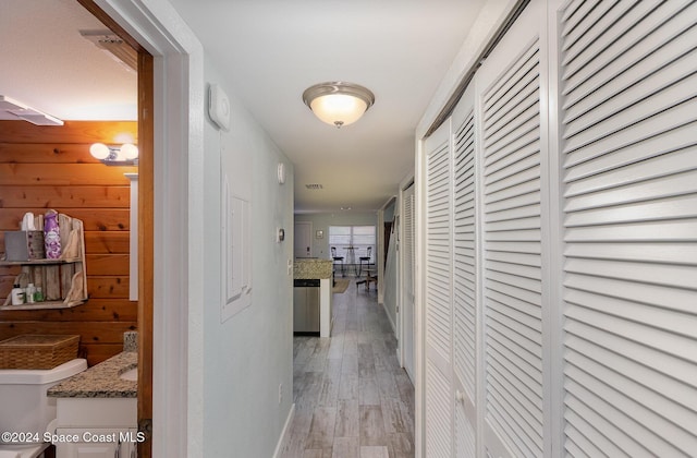 corridor with wooden walls and light hardwood / wood-style flooring