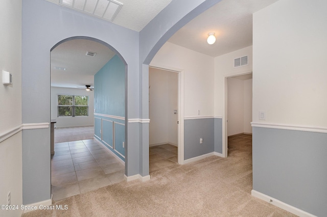 hallway with a textured ceiling and light carpet