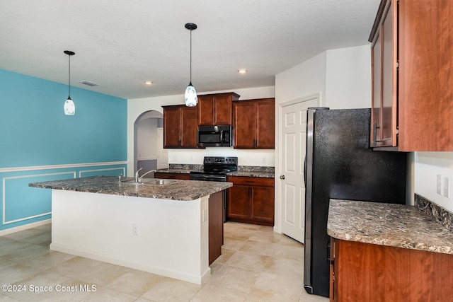 kitchen with a textured ceiling, sink, black appliances, decorative light fixtures, and a center island with sink