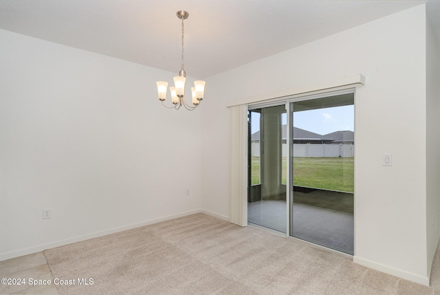 carpeted spare room featuring an inviting chandelier