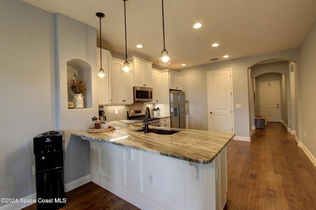 kitchen with white cabinets, decorative light fixtures, dark hardwood / wood-style flooring, kitchen peninsula, and stainless steel appliances