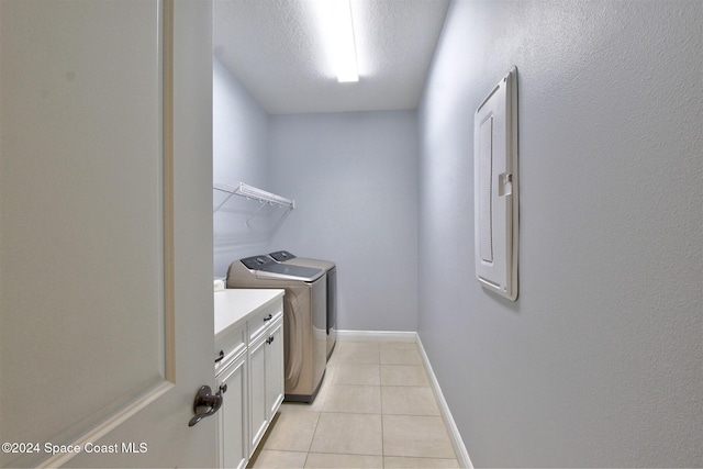 laundry area featuring cabinets, washing machine and dryer, electric panel, a textured ceiling, and light tile patterned floors