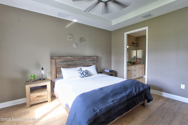 bedroom with hardwood / wood-style flooring, ensuite bathroom, and ceiling fan