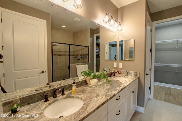 bathroom with tile patterned flooring, vanity, an enclosed shower, and a textured ceiling