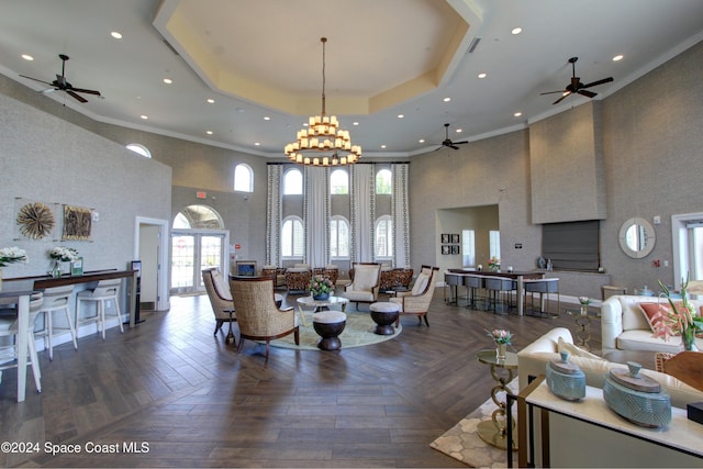 living room with a raised ceiling, dark parquet floors, a towering ceiling, and a notable chandelier