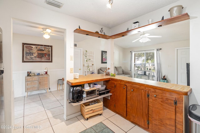 kitchen featuring ceiling fan, light tile patterned flooring, kitchen peninsula, and a textured ceiling