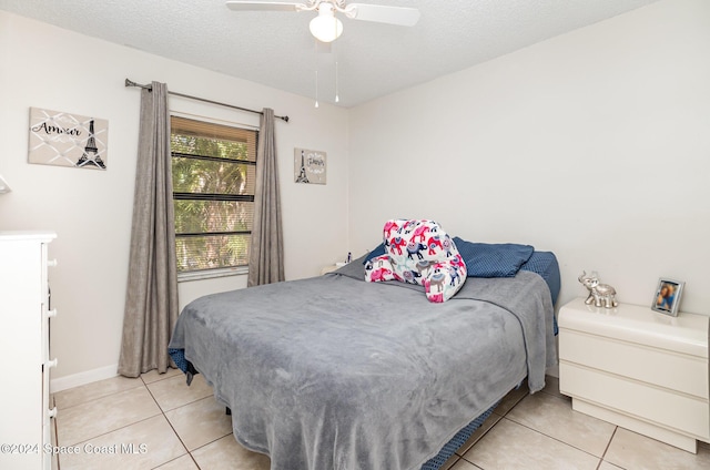 bedroom featuring ceiling fan, light tile patterned flooring, and a textured ceiling