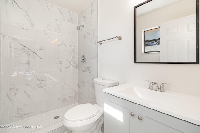 bathroom with tiled shower, vanity, and toilet