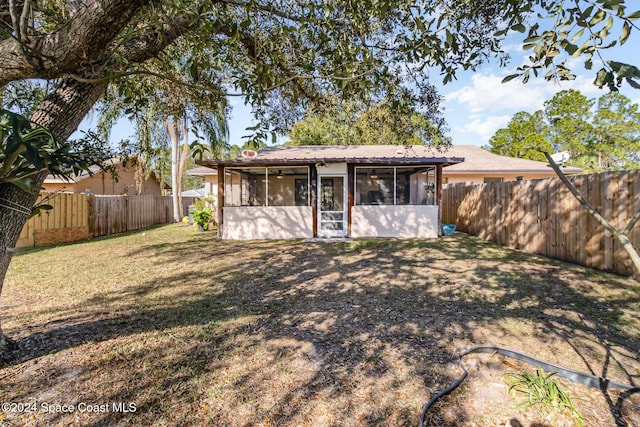 back of property with a sunroom and a lawn