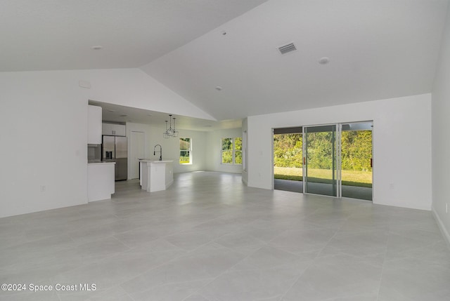 unfurnished living room featuring light tile patterned flooring, high vaulted ceiling, and sink