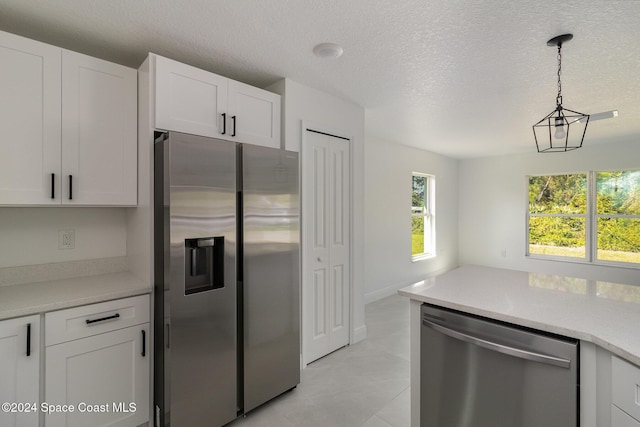 kitchen featuring hanging light fixtures, white cabinetry, stainless steel appliances, and light countertops