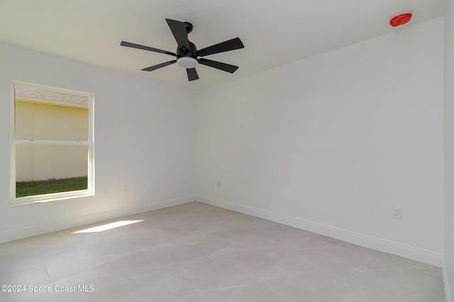 spare room featuring light tile patterned floors, baseboards, and ceiling fan