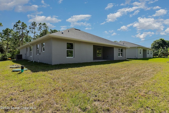 rear view of house with a lawn and central AC unit