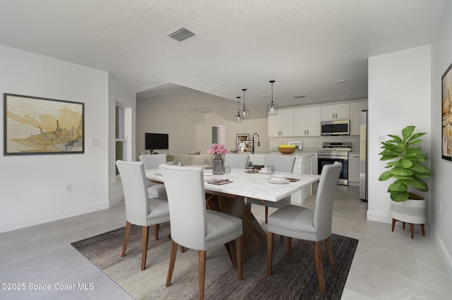 dining space featuring light tile patterned flooring, baseboards, visible vents, and a textured ceiling