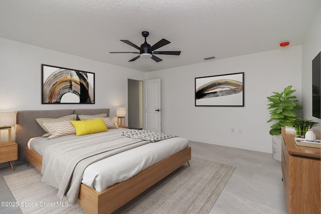 bedroom featuring a ceiling fan, baseboards, visible vents, and a textured ceiling