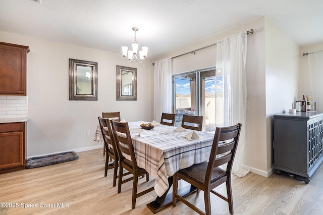 dining area featuring a chandelier, light hardwood / wood-style floors, and a textured ceiling