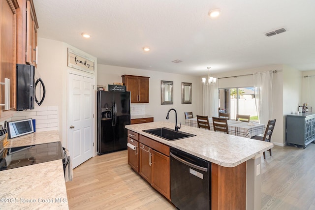 kitchen with sink, tasteful backsplash, a chandelier, a kitchen island with sink, and black appliances