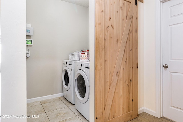 clothes washing area with light tile patterned floors, a barn door, and separate washer and dryer