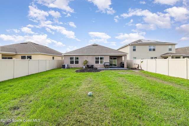 rear view of house featuring a lawn, a patio, and central AC