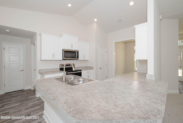 kitchen featuring lofted ceiling, wood-type flooring, white cabinetry, kitchen peninsula, and stainless steel appliances