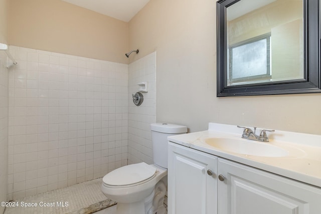 bathroom featuring a tile shower, vanity, and toilet