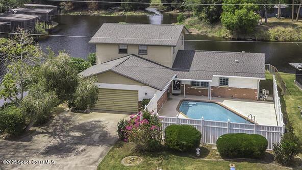 850 Cardinal Rd, Cocoa, FL 32926 - rear view of house featuring a fenced backyard, concrete driveway, a water view, and an attached garage