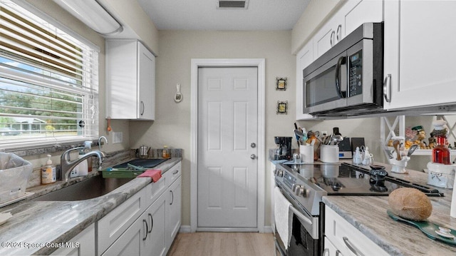 kitchen with light stone counters, white cabinets, and stainless steel appliances