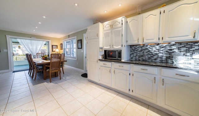 kitchen with dark stone countertops, white cabinetry, crown molding, and light tile patterned floors