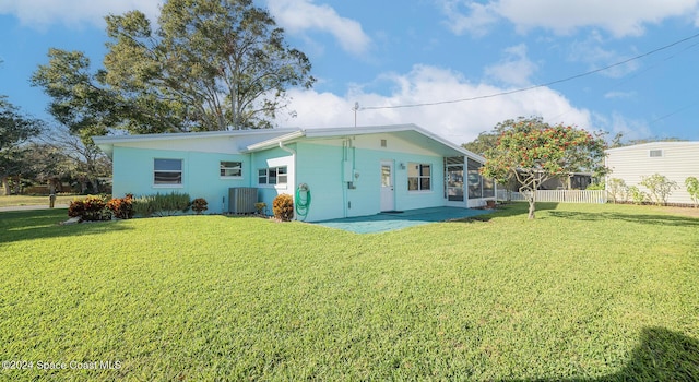 rear view of house with central AC, a patio area, and a lawn