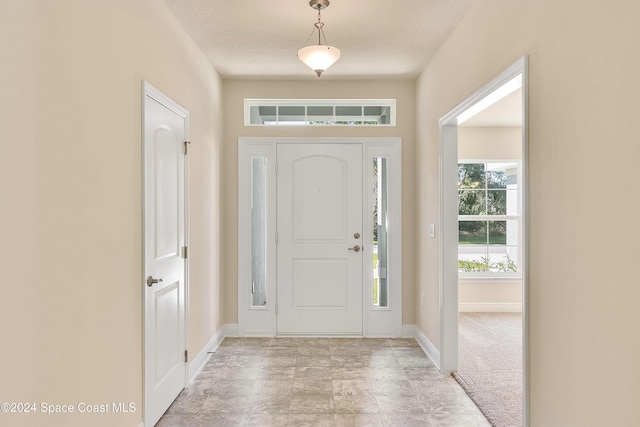 foyer with light colored carpet and a textured ceiling