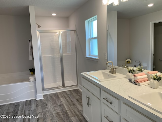 698 De Groodt Rd SW, Palm Bay, FL 32908 - full bathroom featuring a stall shower, wood finished floors, double vanity, a bath, and recessed lighting