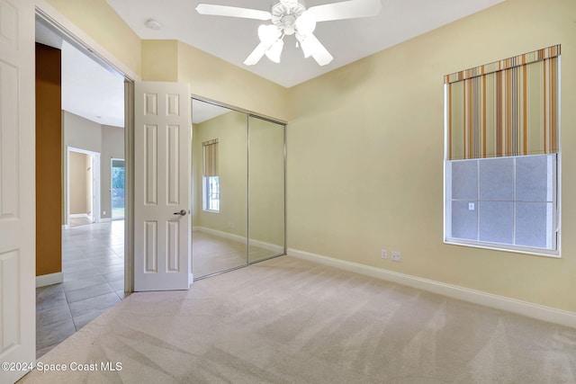 unfurnished bedroom featuring light carpet, a closet, and ceiling fan