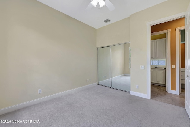 unfurnished bedroom featuring light carpet, a closet, and ceiling fan