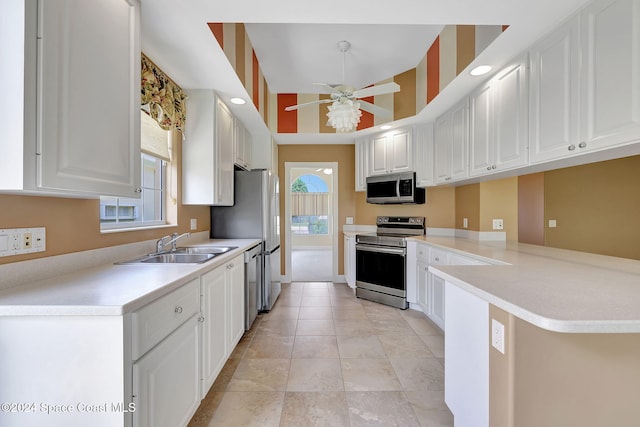 kitchen featuring kitchen peninsula, stainless steel appliances, ceiling fan, sink, and white cabinetry