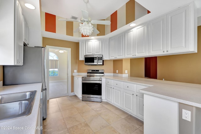 kitchen with kitchen peninsula, ceiling fan, white cabinets, and stainless steel appliances