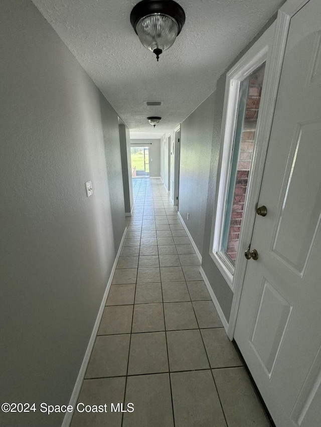 hallway with light tile patterned floors and a textured ceiling