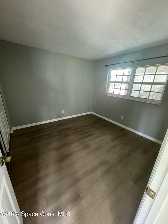 unfurnished room with a textured ceiling and dark hardwood / wood-style floors