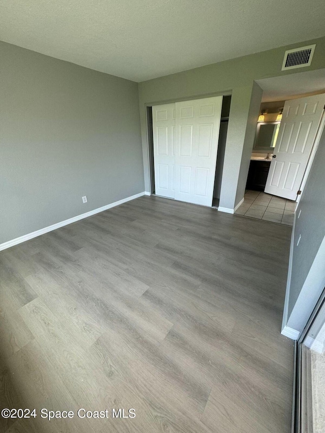 unfurnished bedroom featuring a closet, a textured ceiling, and light wood-type flooring