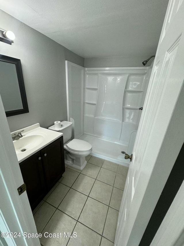 bathroom featuring tile patterned floors, walk in shower, vanity, a textured ceiling, and toilet