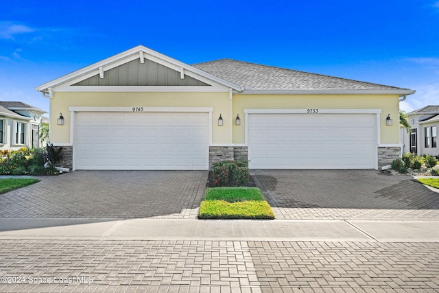 view of front of house with a garage, stone siding, decorative driveway, and stucco siding