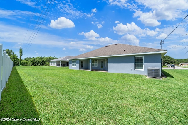 back of house with central AC unit and a yard