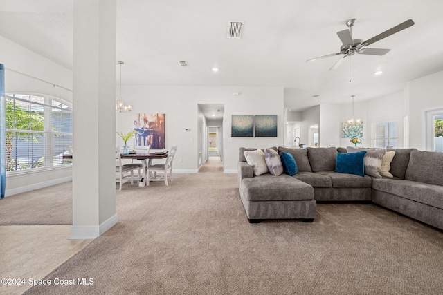 living room featuring ceiling fan with notable chandelier and light colored carpet