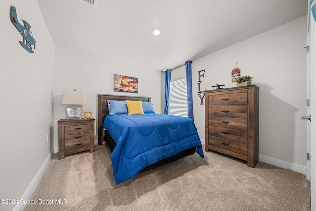 bedroom featuring light colored carpet and a textured ceiling