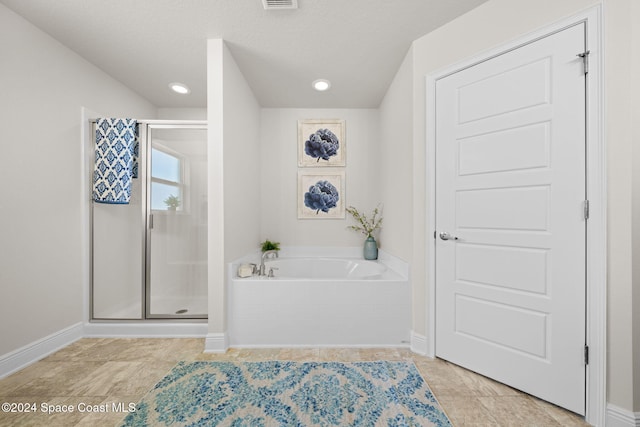 bathroom with a textured ceiling and independent shower and bath