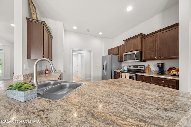 kitchen with kitchen peninsula, appliances with stainless steel finishes, dark brown cabinetry, and sink