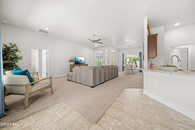 living room featuring light colored carpet and ceiling fan with notable chandelier