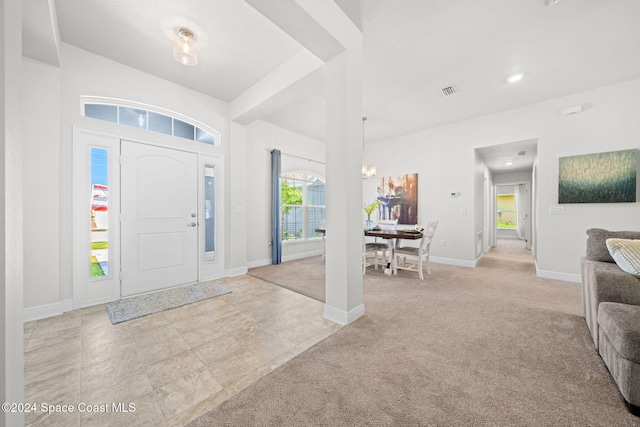 entrance foyer with light colored carpet and a chandelier