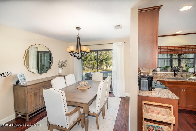 dining room with dark wood-type flooring, a notable chandelier, and sink