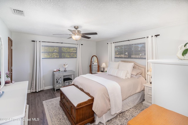 bedroom featuring a textured ceiling, ceiling fan, dark wood-type flooring, and multiple windows