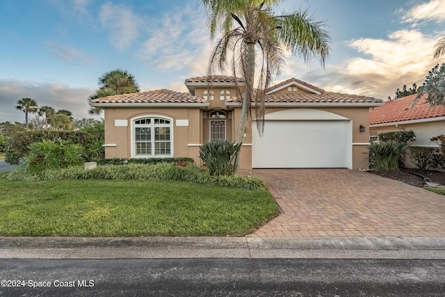 mediterranean / spanish-style home featuring a garage and a yard